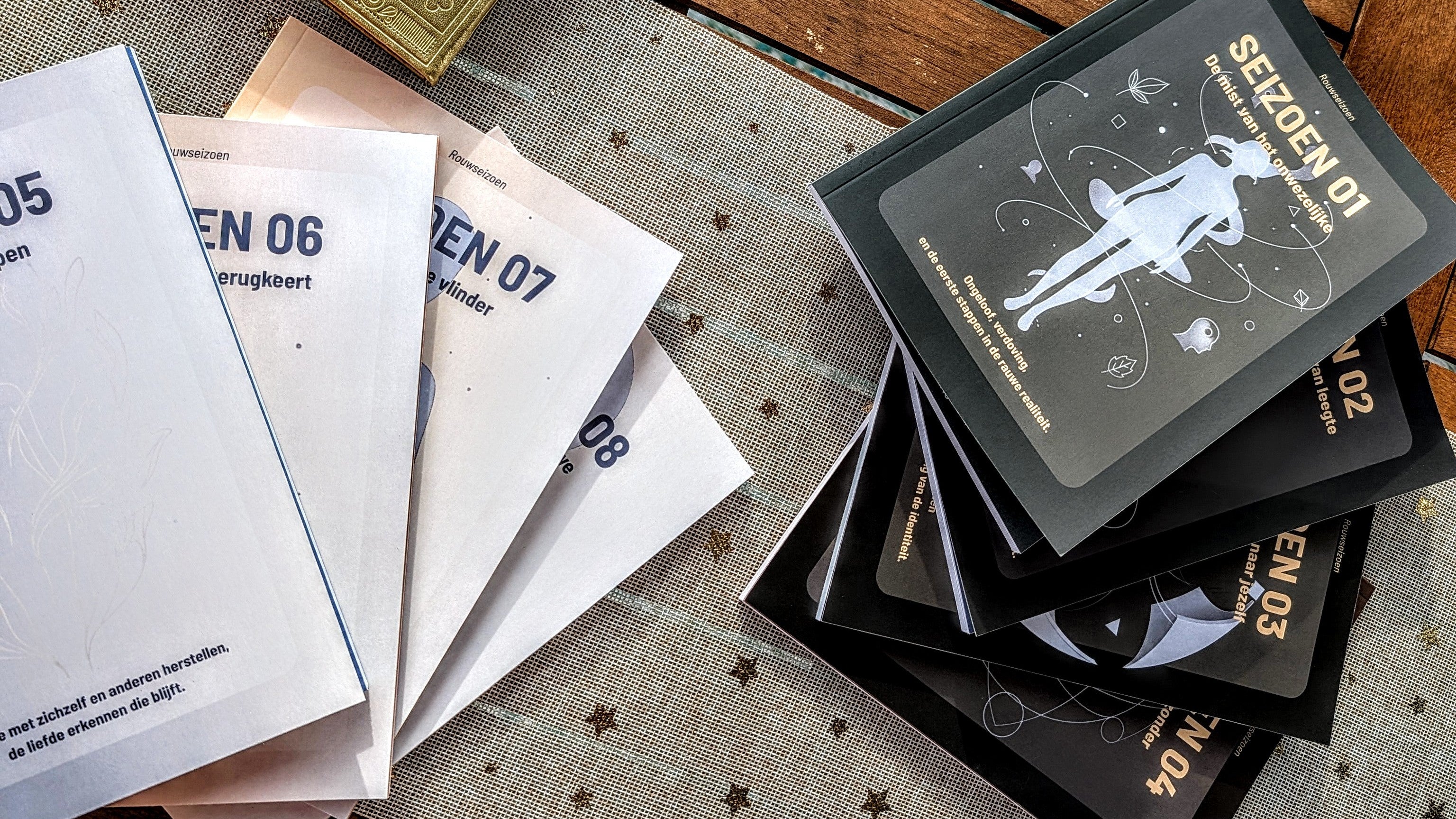 De volledige collectie Rouwseizoenen reflectieboeken (rouwdagboeken) uitgestald op tafel met een kleedje met sterretjes onder de boekjes.