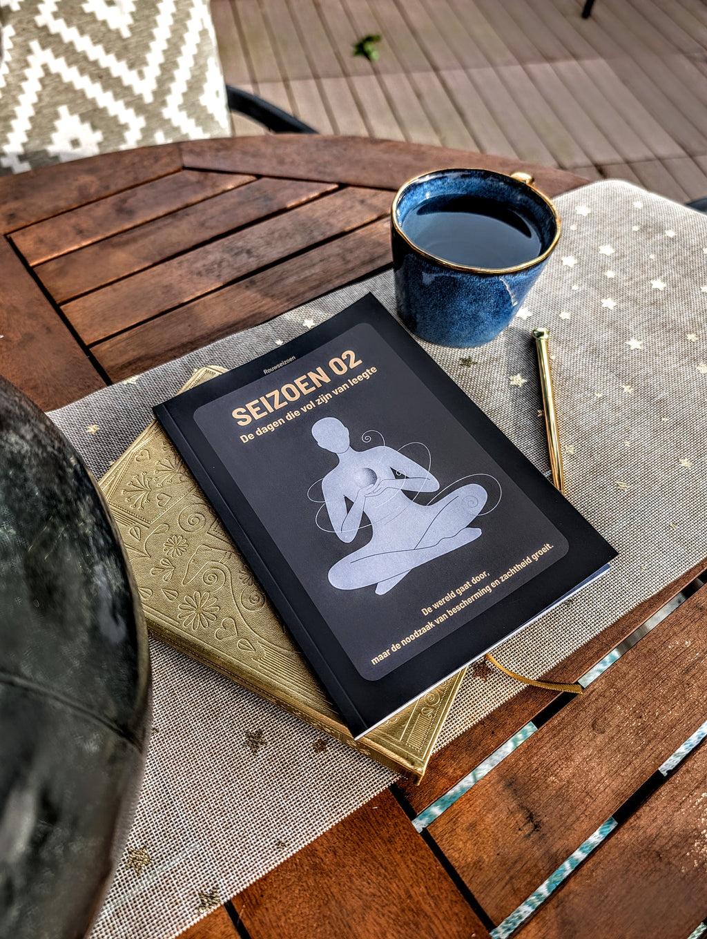 Seizoen 02 op tafel bovenop een notitieboek met een kop thee en pen ernaast.