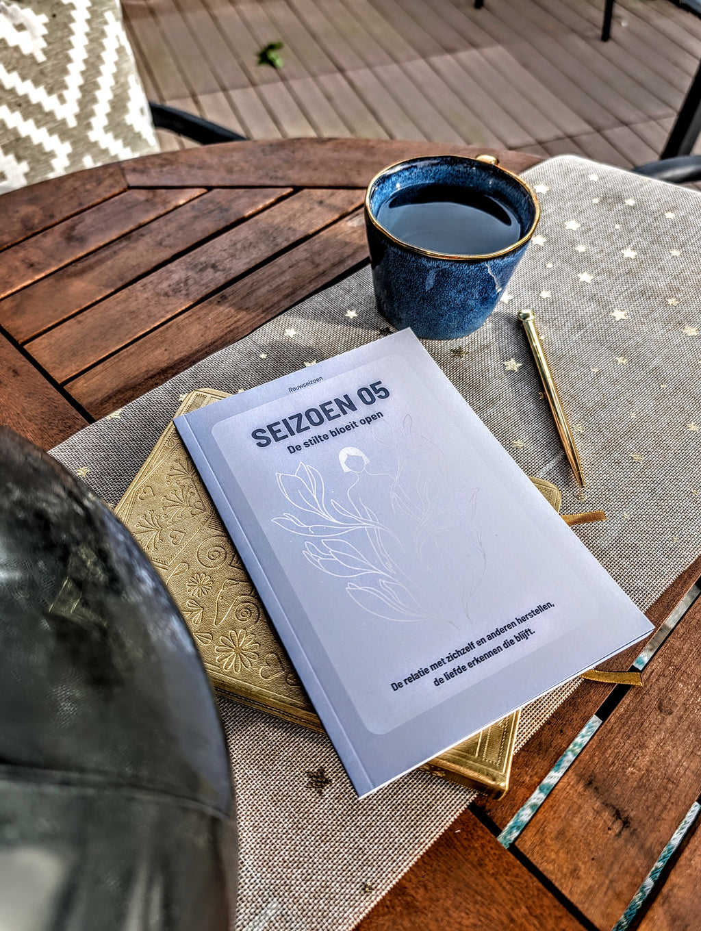 Seizoen 05 op tafel bovenop een notitieboek met een kop thee en pen ernaast