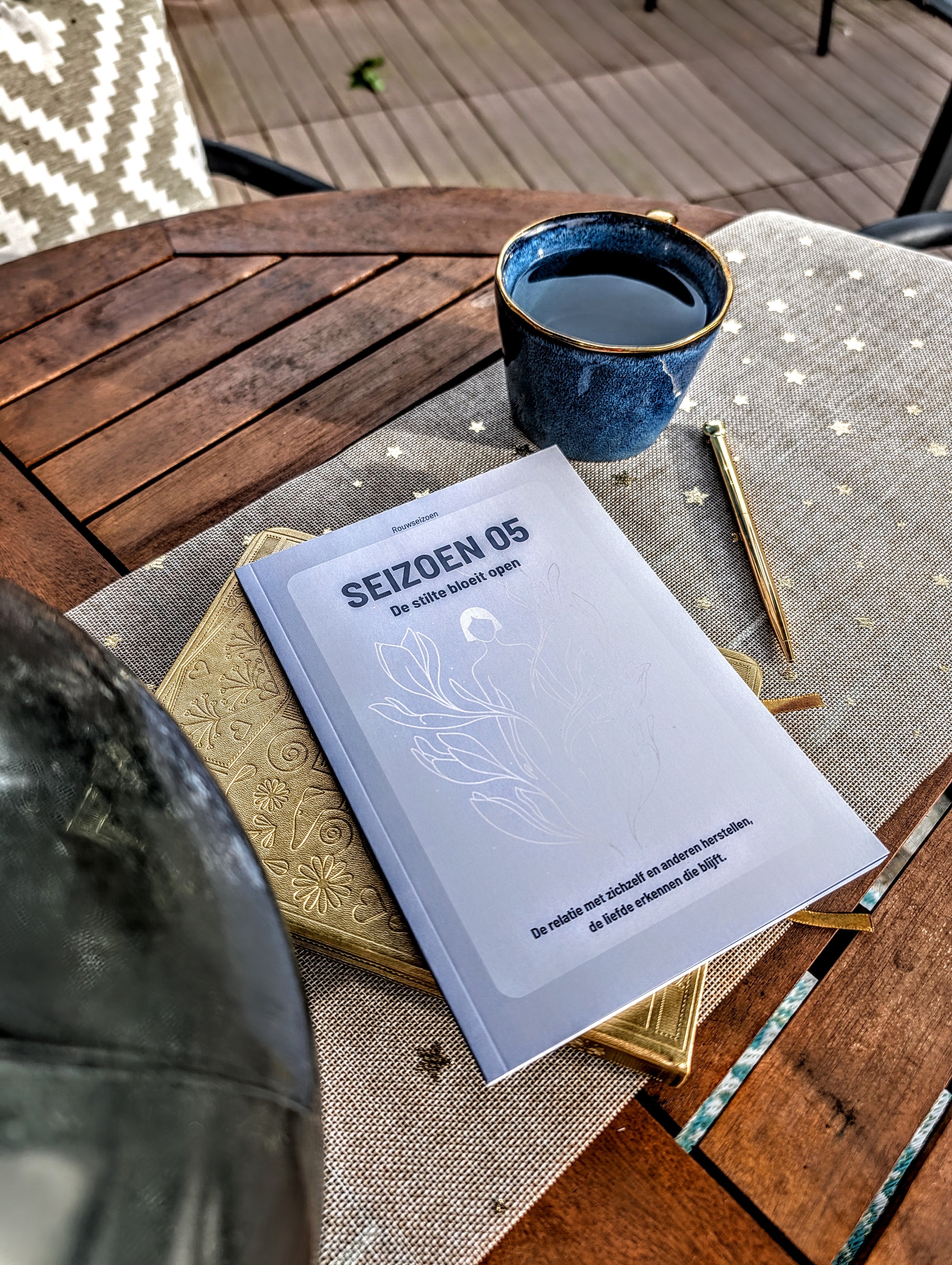 Seizoen 05 op tafel bovenop een notitieboek met een kop thee en pen ernaast