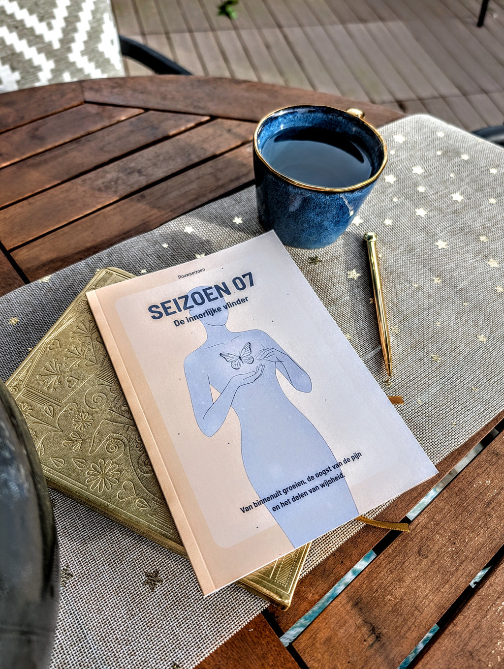 Seizoen 07 op tafel bovenop een notitieboek met een kop thee en pen ernaast