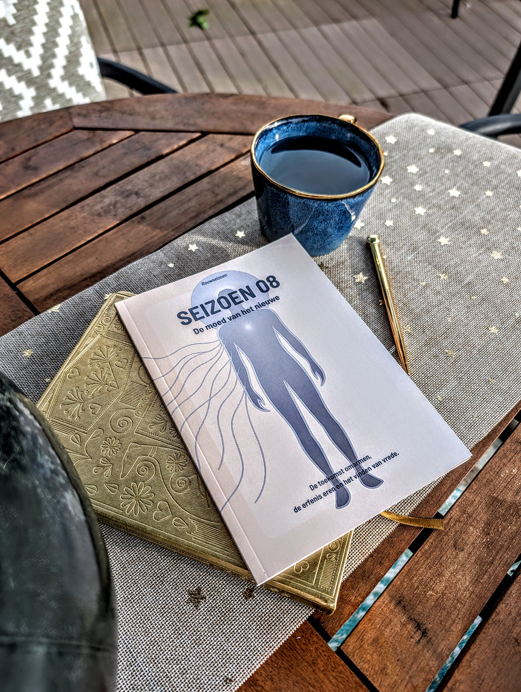 Seizoen 08 op tafel bovenop een notitieboek met een kop thee en pen ernaast